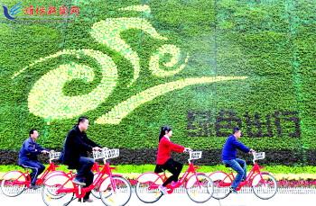市民騎公共自行車(chē)路過(guò)市人民廣場(chǎng)一處花壇。記者 張馳